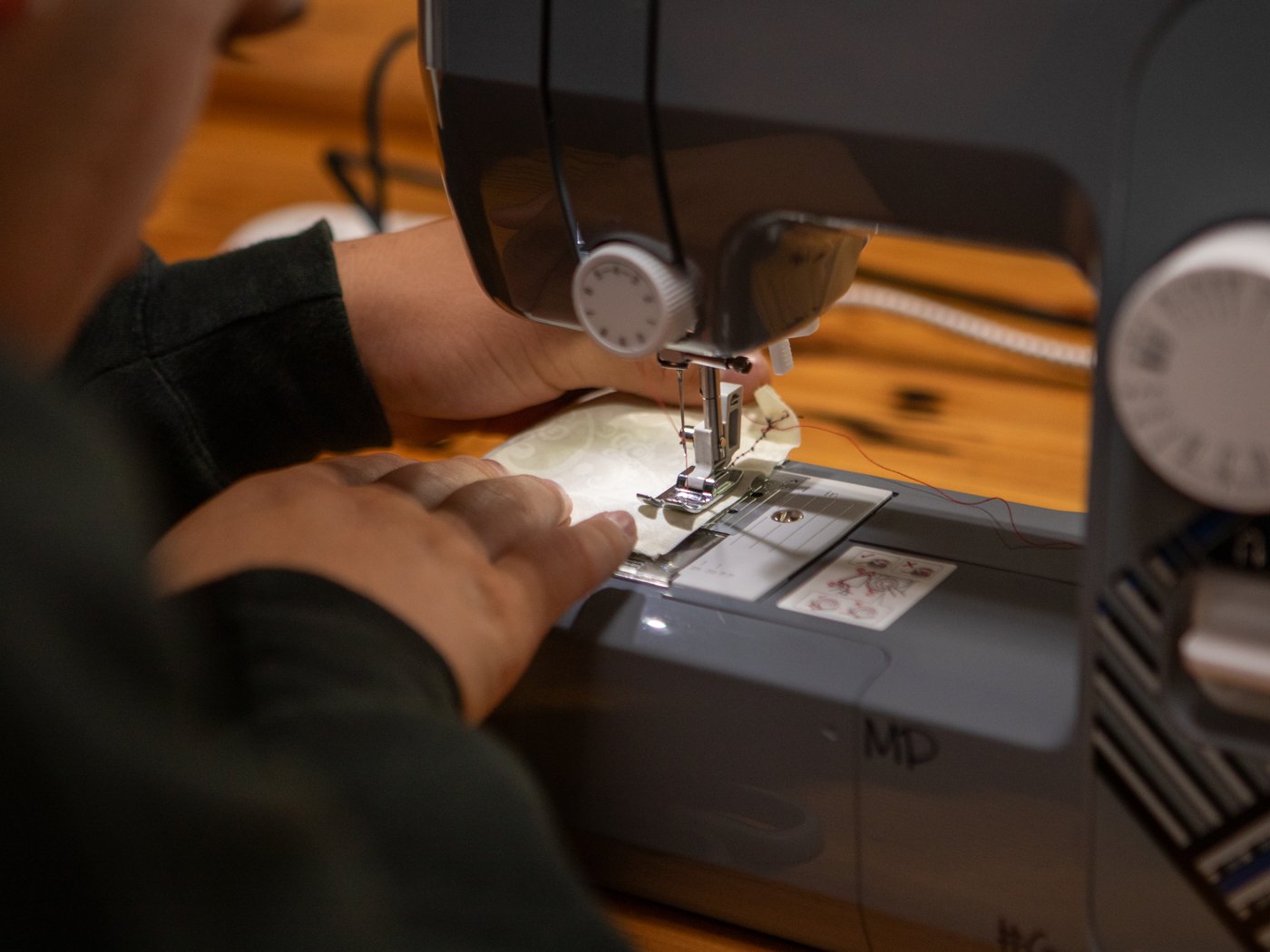 A student guiding fabric through a sewing machine