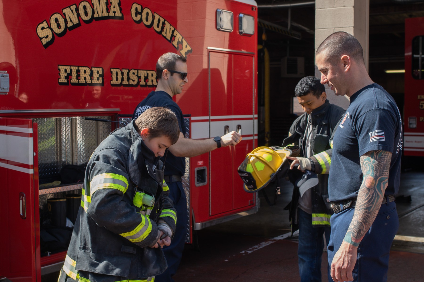 Students and a firefighter working with equipment beside a fire engine