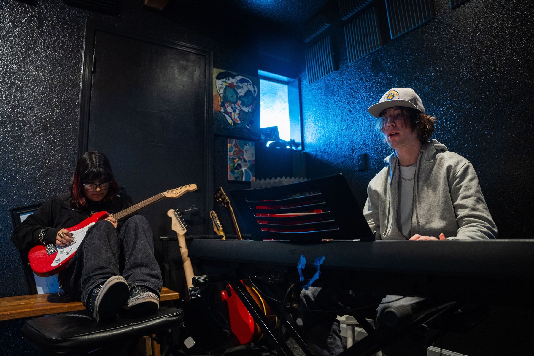 Two students playing guitar and keyboard in a music studio