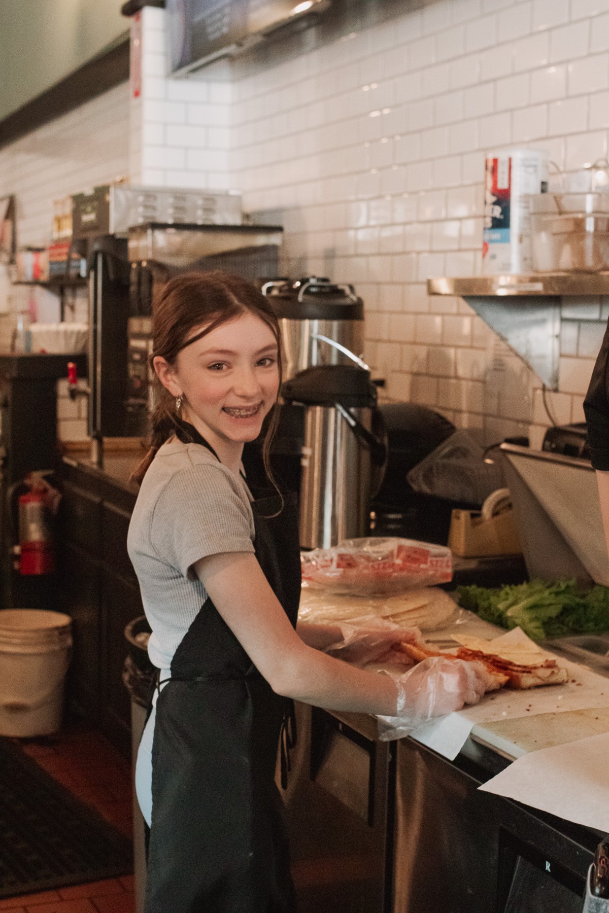 A student preparing food behind a café counter