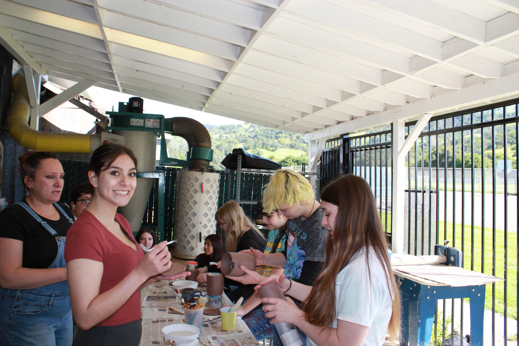 Students and mentors working with clay at an outdoor table
