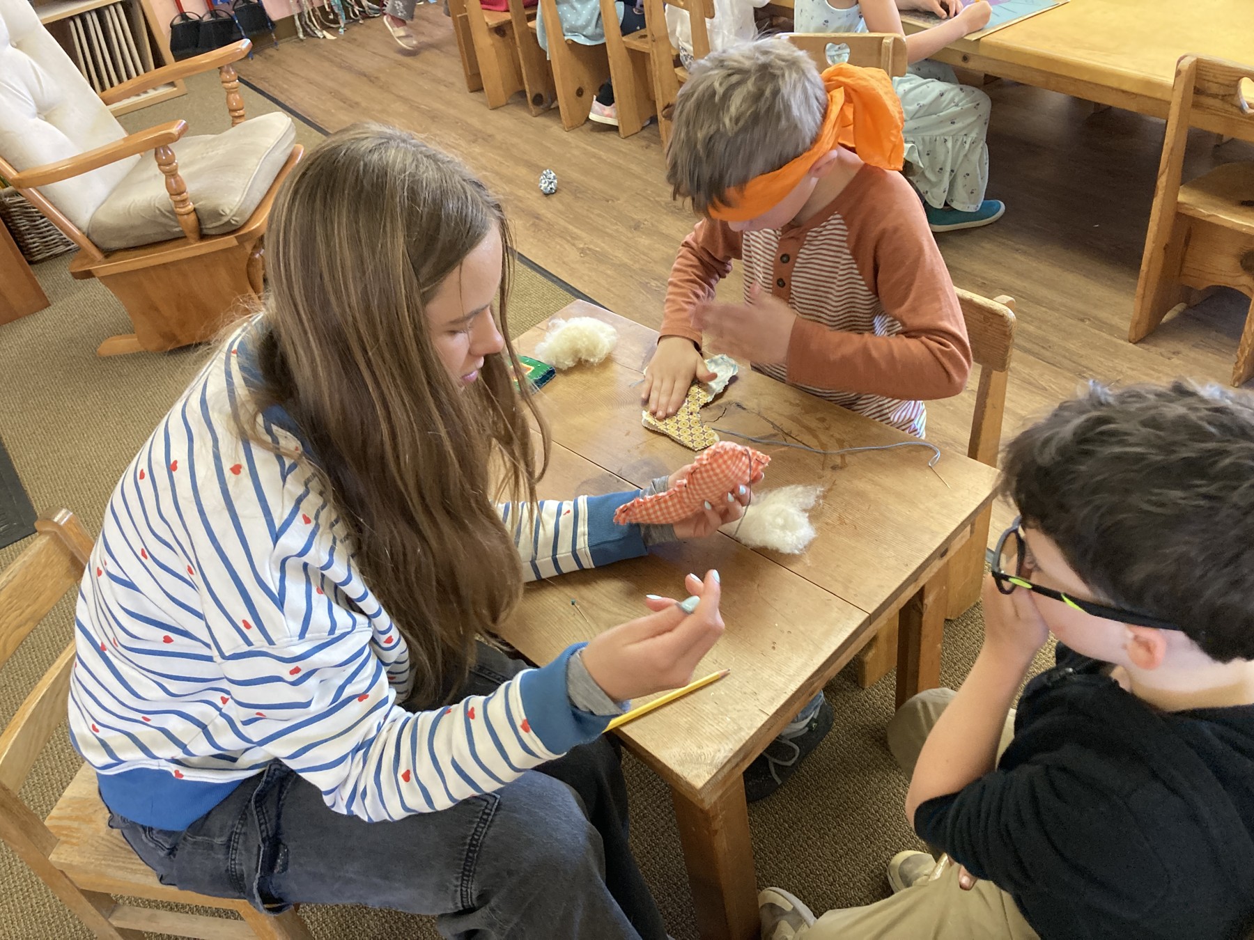 A young mentor supporting children with a classroom activity